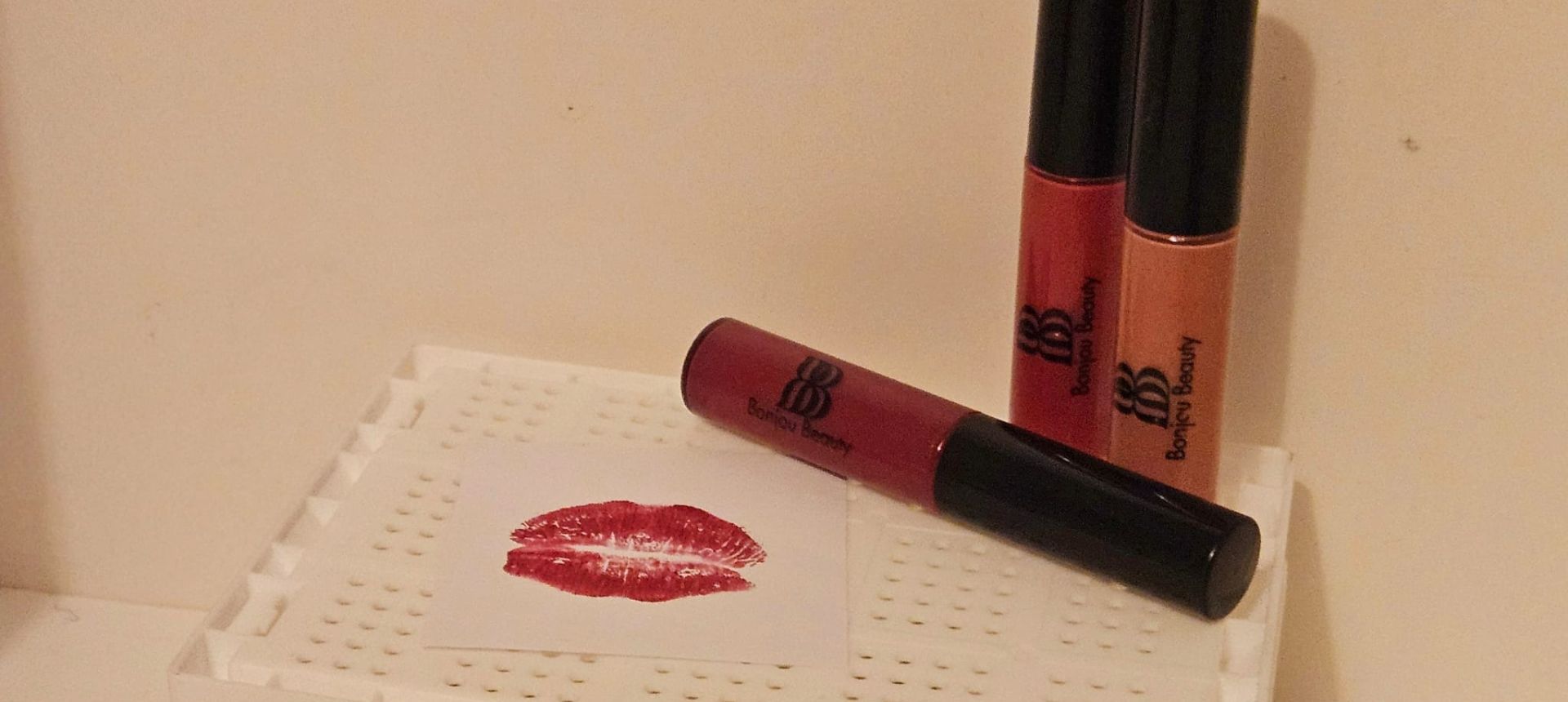 Three lip gloss shades on a box with a lip imprint
