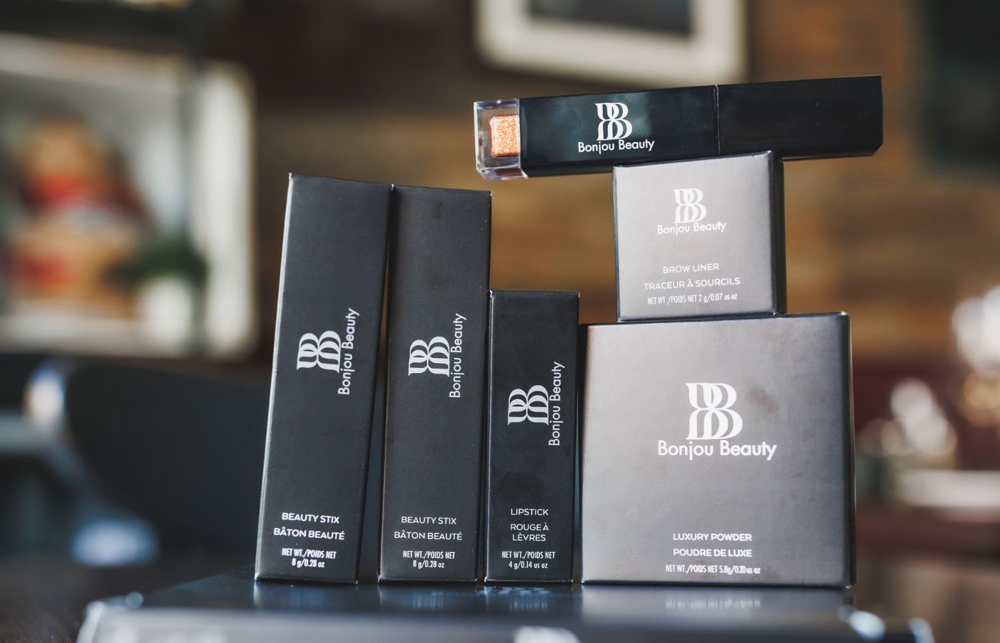 Bonjou Beauty Makeup Products in Packaging Stacked on Table with Blurred Background