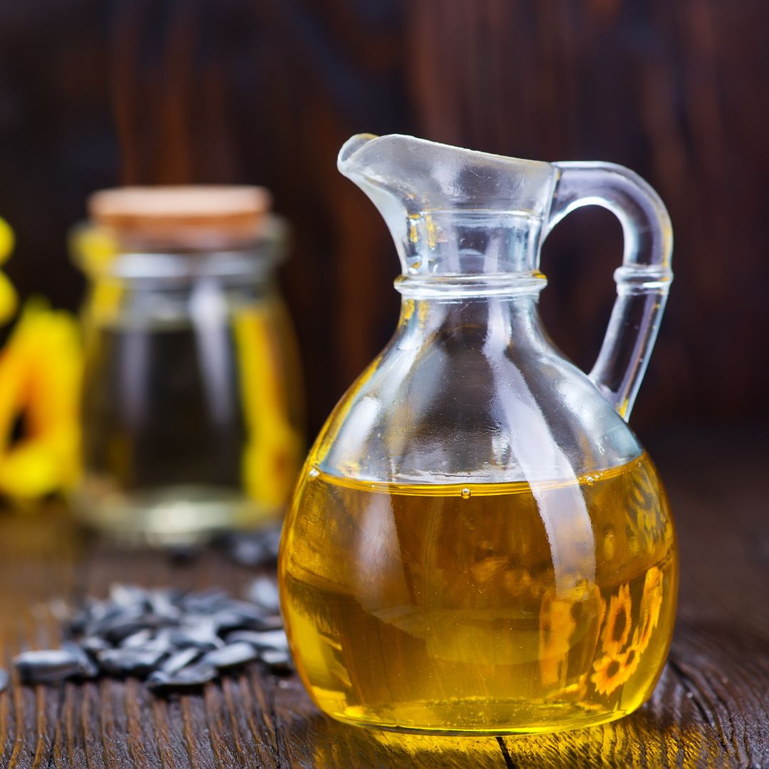 Bottles of sunflower seed oil with sunflower seeds blurred on wood table