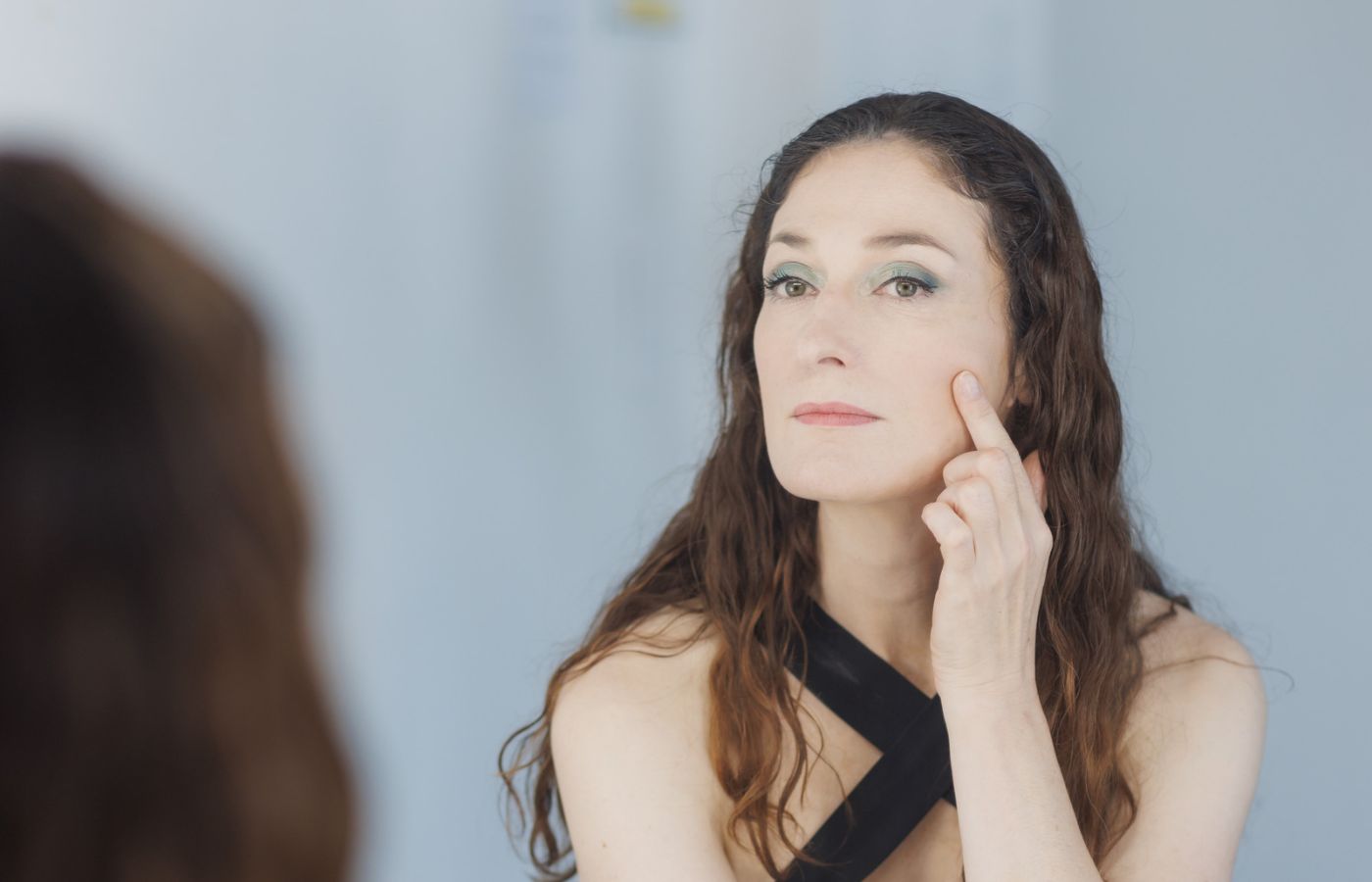 woman applying cream to face in mirror