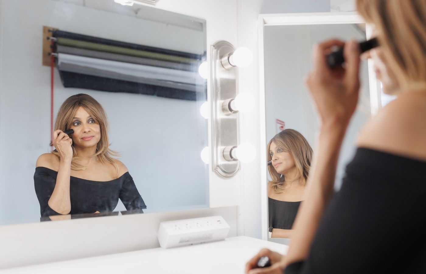 woman putting on makeup in a mirror