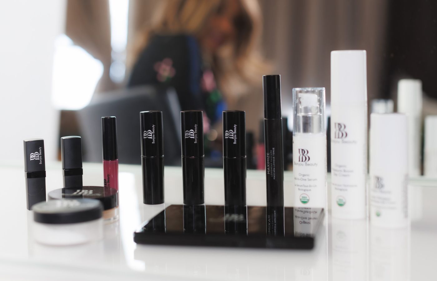 Bonjou Beauty skincare and makeup products on a table with a mirror