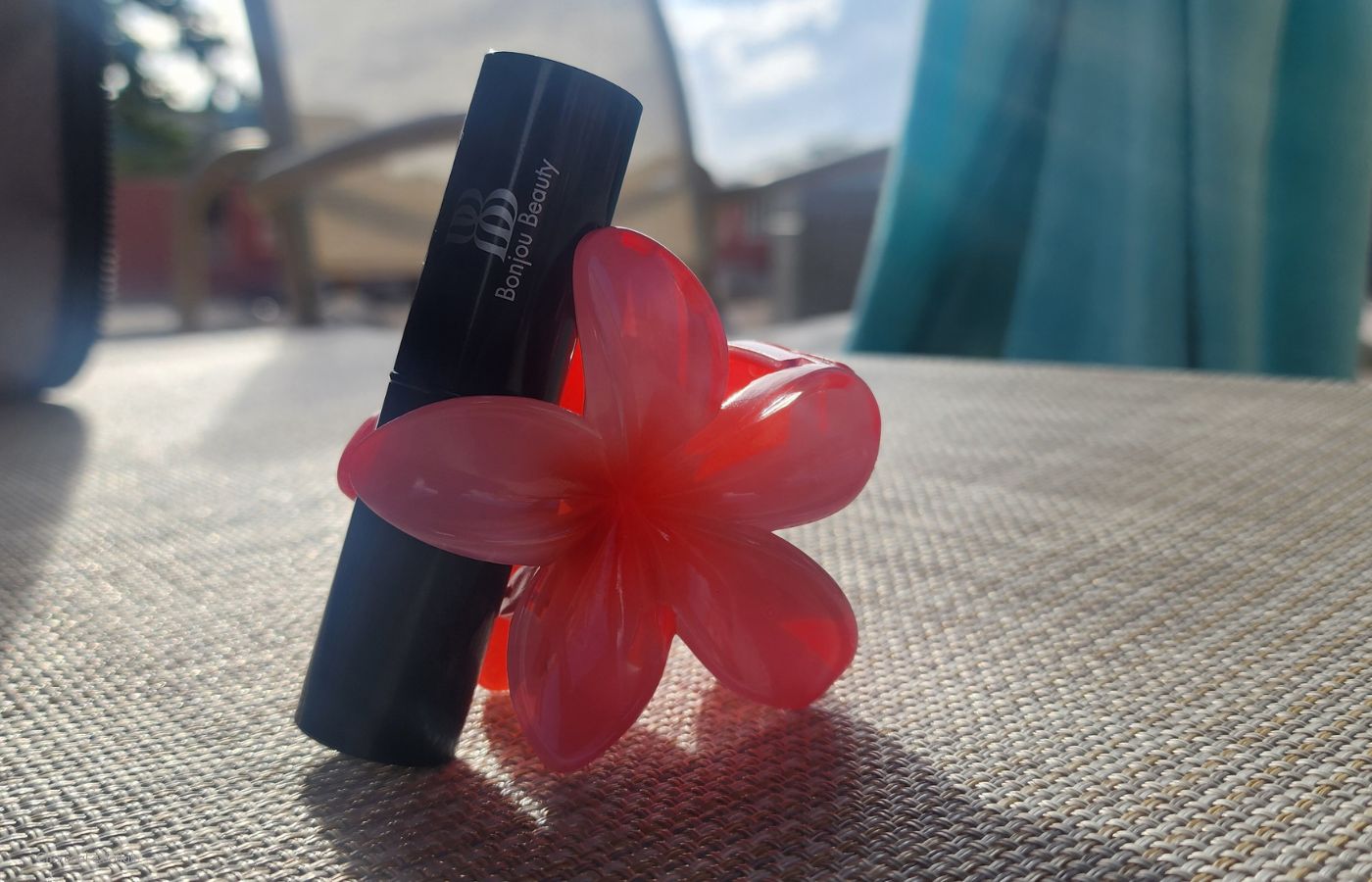 Beauty product with a ceramic flower on a beige surface in the sun