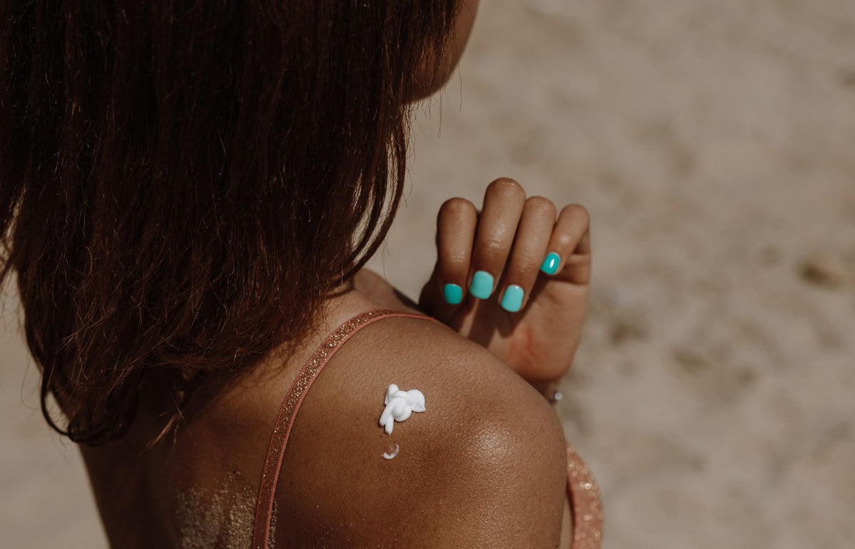 Woman applying sunscreen on shoulder on the beach