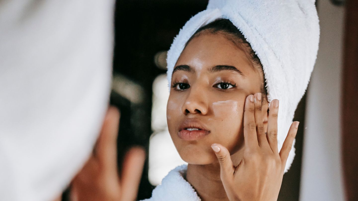 woman putting on day cream in mirror