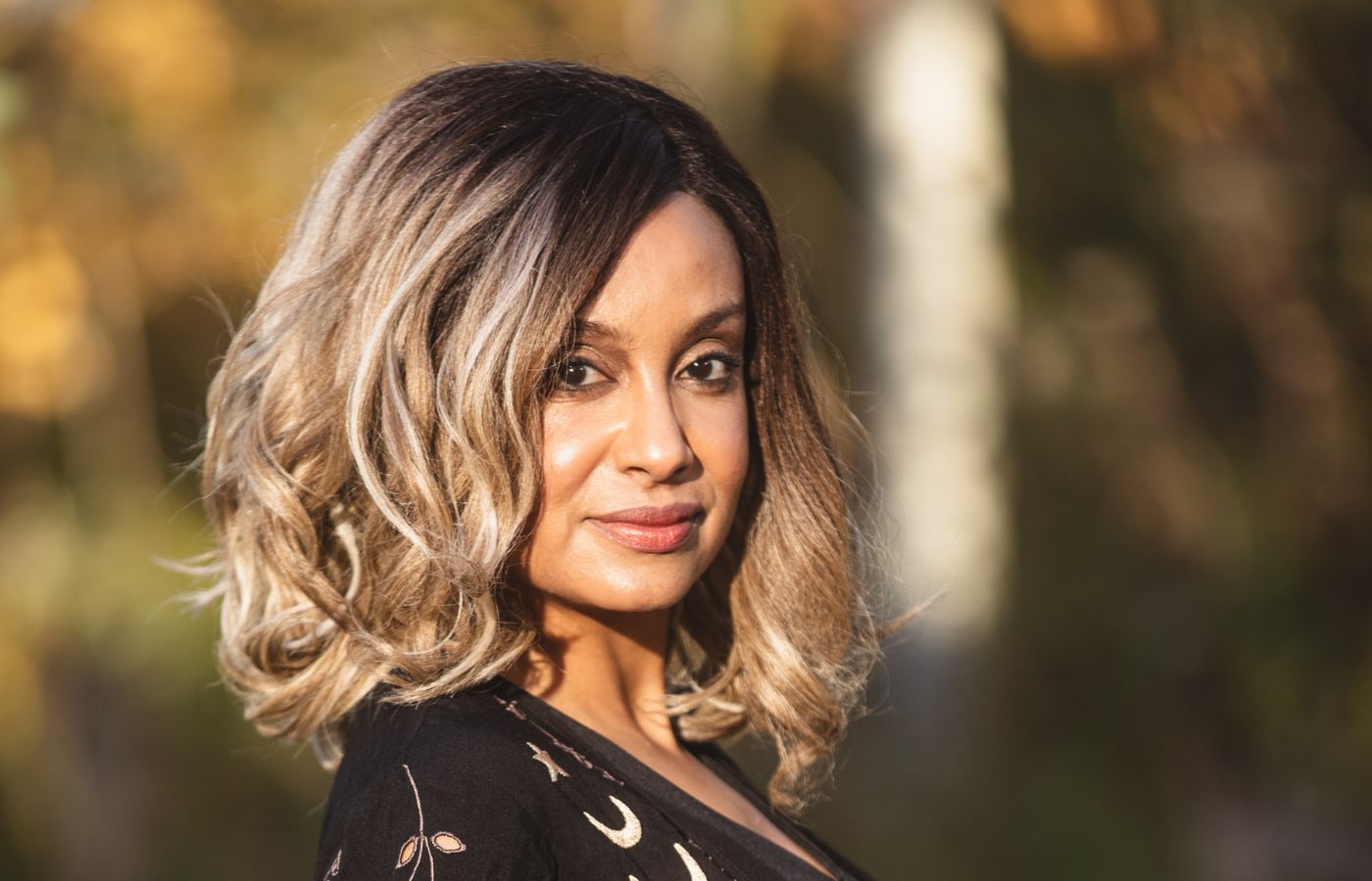woman wearing monochromatic makeup with fall leaves in the background