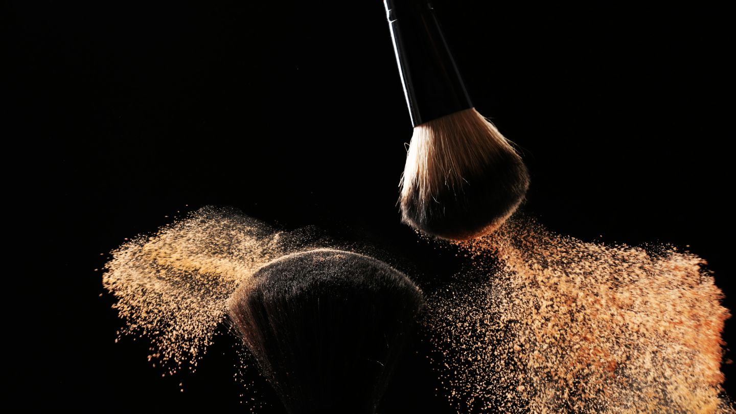 2 Makeup brushes with mineral foundation powder coming off of them