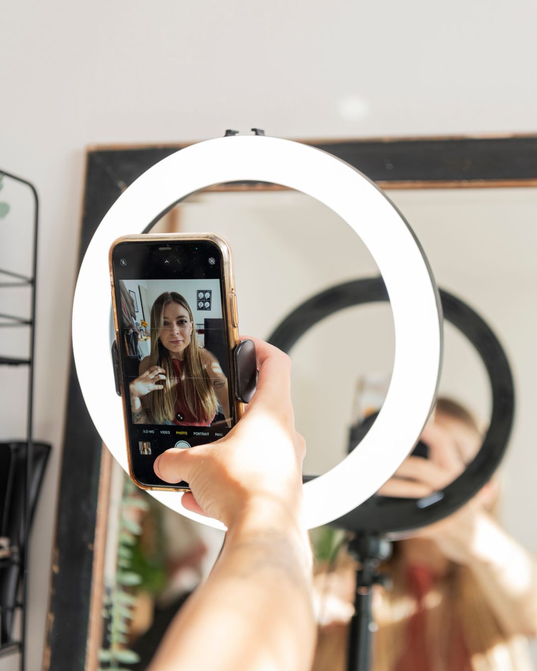Influencer taking a selfie with a glowing ring light mirror and their reflection in the ring light. 