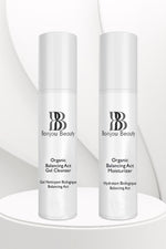 Two bottles of Bonjou Beauty Organic Balancing Act products, the moisturizer and cleanser, on a white table and background