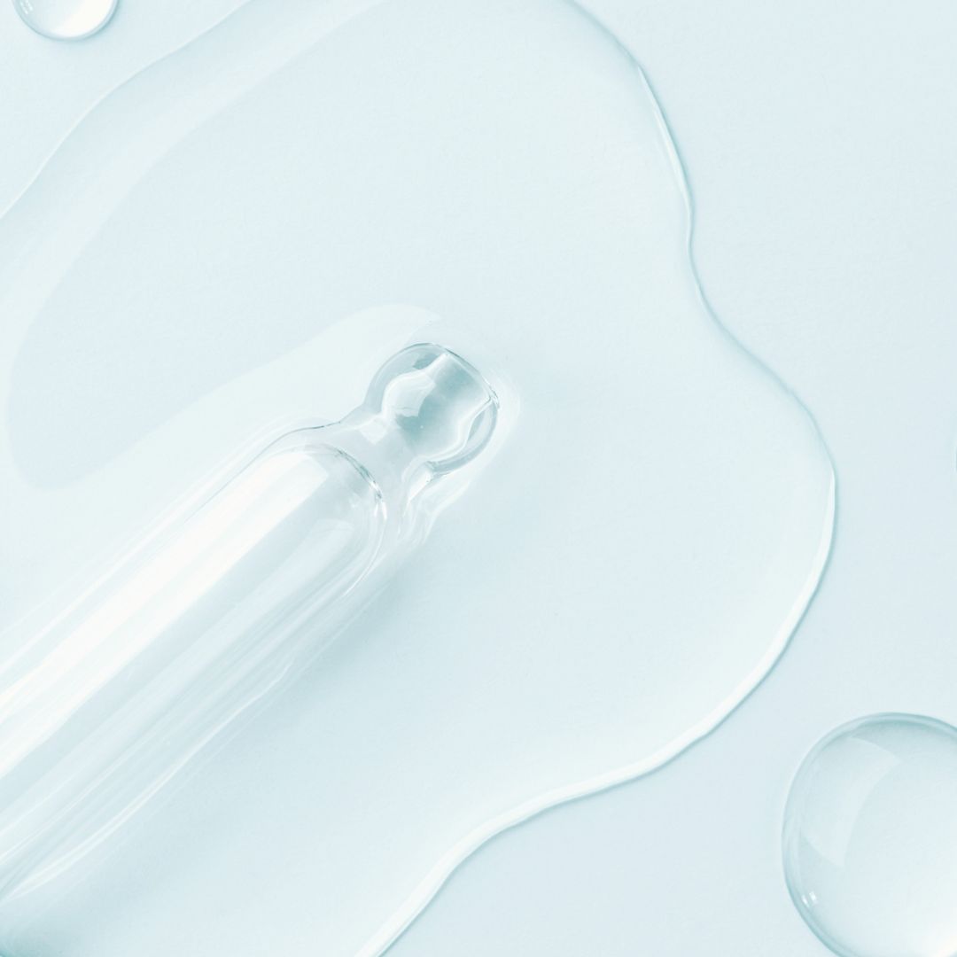 Close-up of a dropper with clear Niacinamide on a light blue background