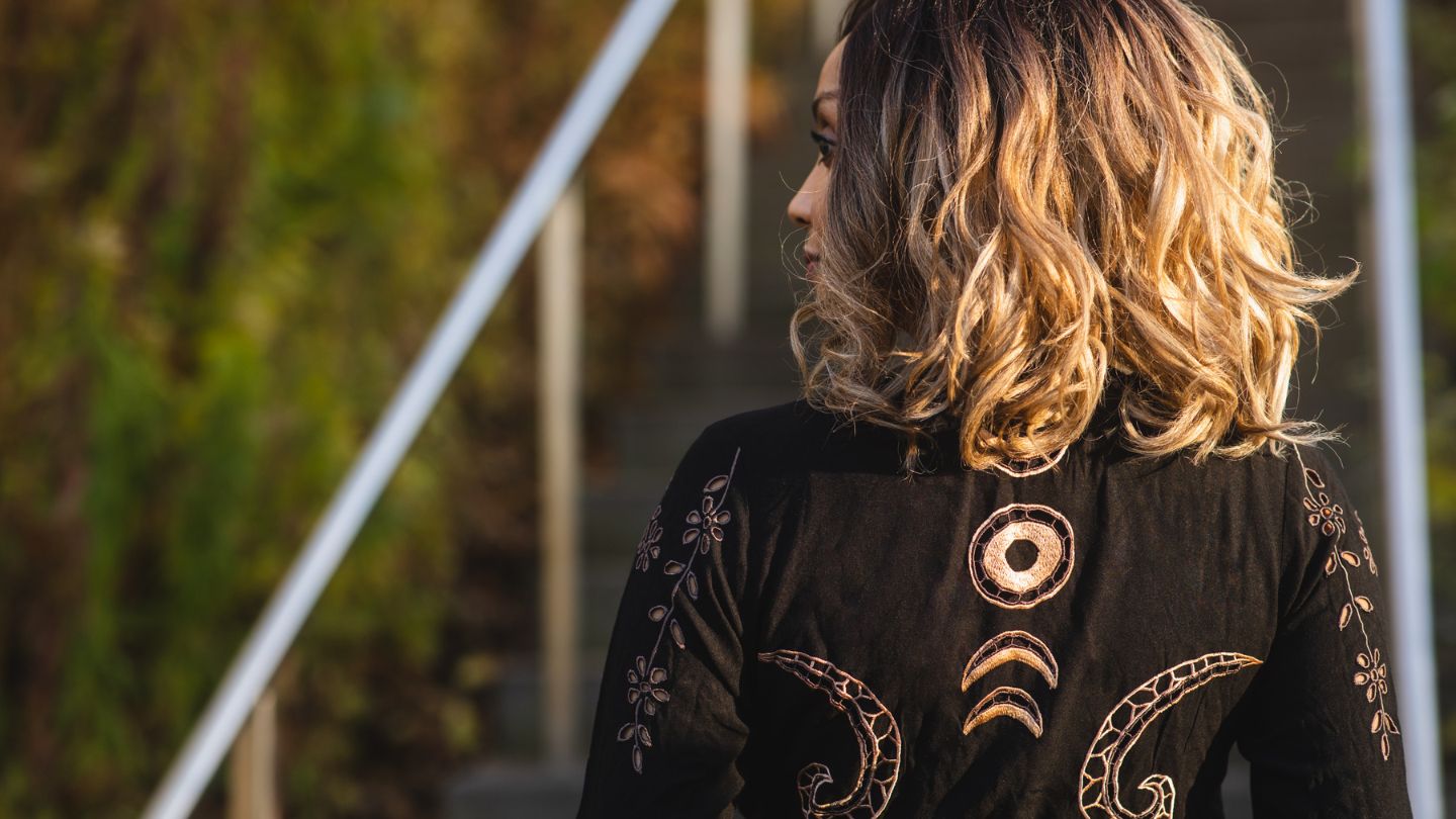 Person wearing a black embroidered jacket with gold designs outdoors