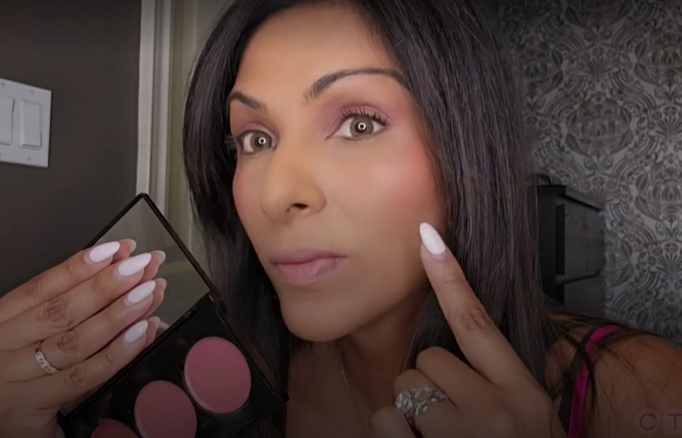 Woman applying Bonjou Beauty makeup with a palette in a bathroom setting