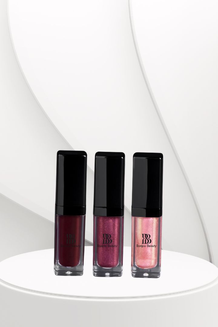 Three lip gloss bottles with black caps on a white platform