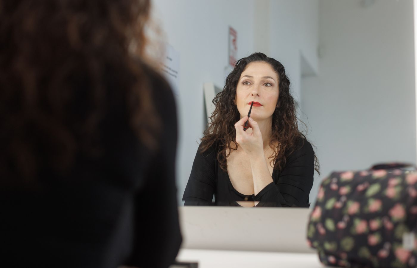 Woman applying lipstick in front of a mirror