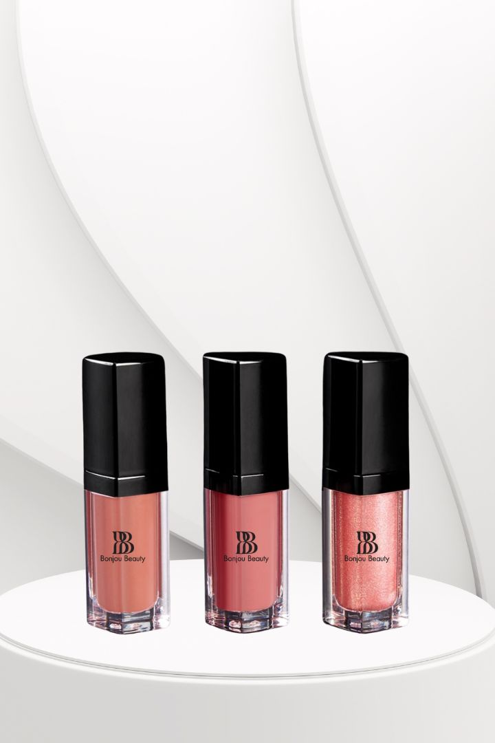 Three bottles of pink Bonjou Beauty lip gloss on a white background