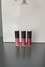 3 Bonjou Beauty vegan lip glosses on a dark table with a white Bonjou Beauty bag