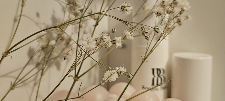 Skincare products behind flowers and pink balloons